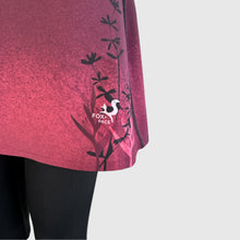 Ielādēt video galerijas pārlūkā, Women's A-line running skirt with an ombre (burgundy and pink) base and a Strelitzia floral pattern. The skirt has built-in black mid-length shorts with side pockets and a zipper pocket on the back.
