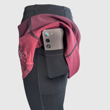 Ielādēt video galerijas pārlūkā, Women's A-line running skirt with an ombre (burgundy and pink) base and a Strelitzia floral pattern. The skirt has built-in black mid-length shorts with side pockets and a zipper pocket on the back.
