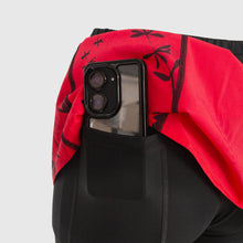 Ielādēt video galerijas pārlūkā, Women's A-line running skirt with an ombre (burgundy and pink) base and a Strelitzia floral pattern. The skirt has built-in black mid-length shorts with side pockets and a zipper pocket on the back.